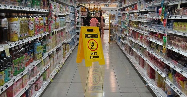 A yellow caution sign in the middle of a store aisle.