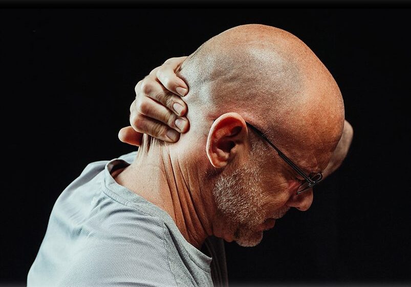 A bald man with glasses is holding his head